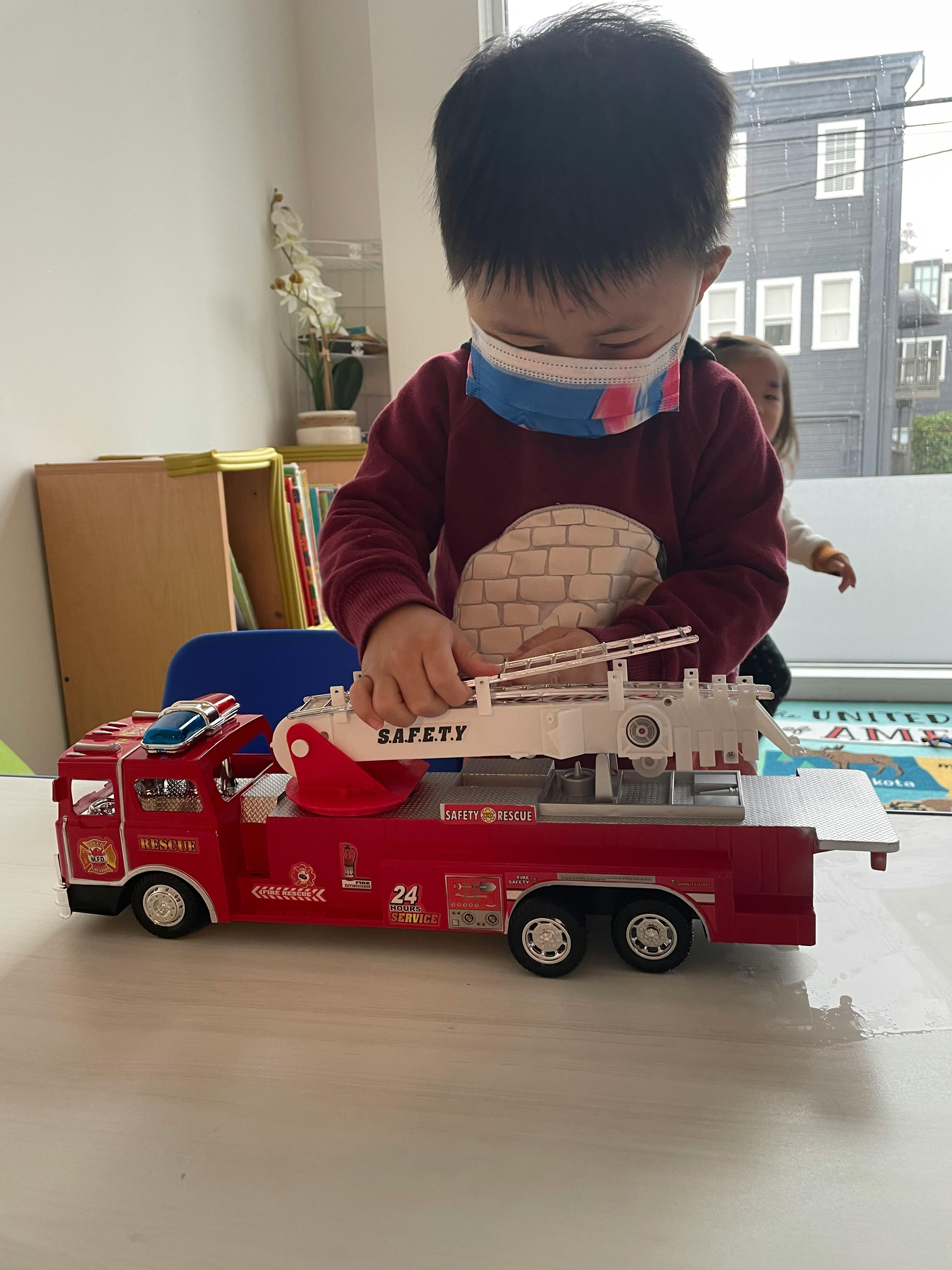 Child playing with a toy fire truck