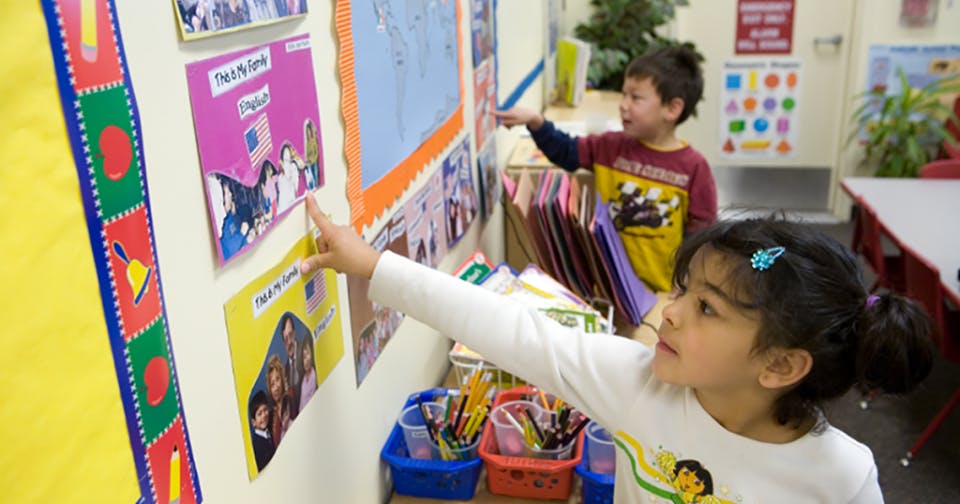 Child pointing at a display on a wall in a classroom