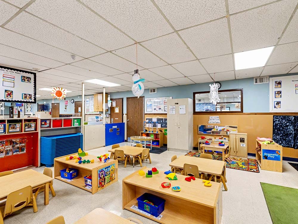 Classroom with small tables, chairs, and play areas