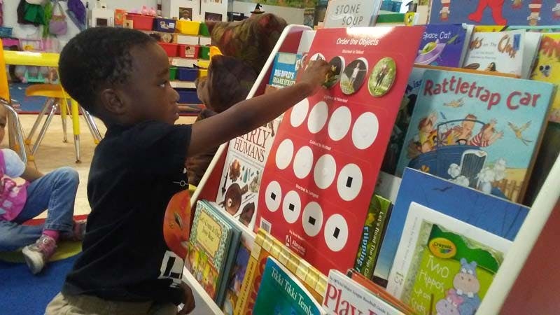 Child reaching for a book on a shelf