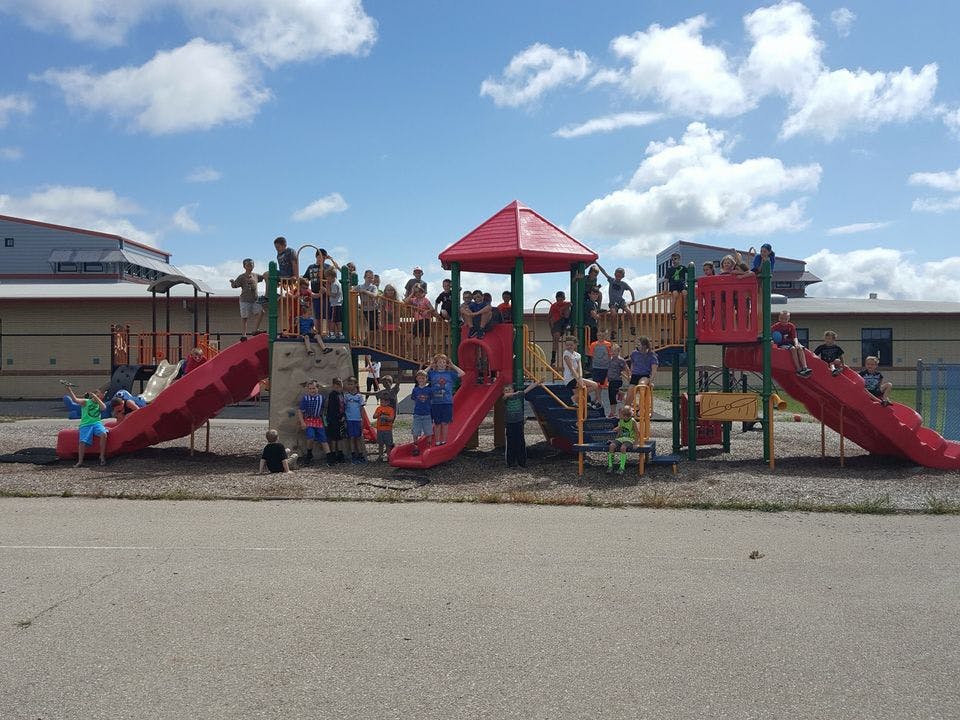 Children playing on a red and brown playground structure