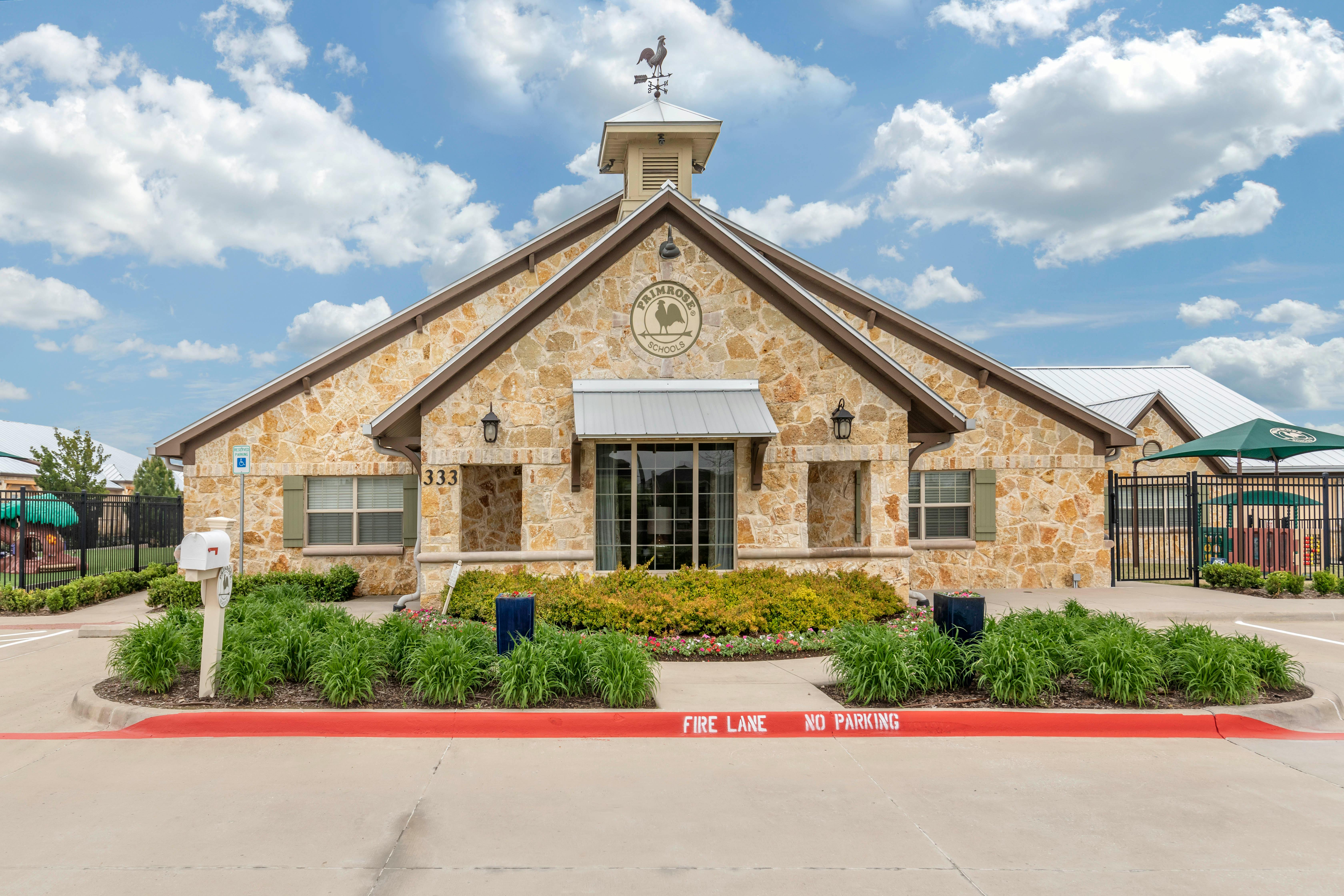 Stone building with "Primrose Schools" logo, cupola, and weather vane