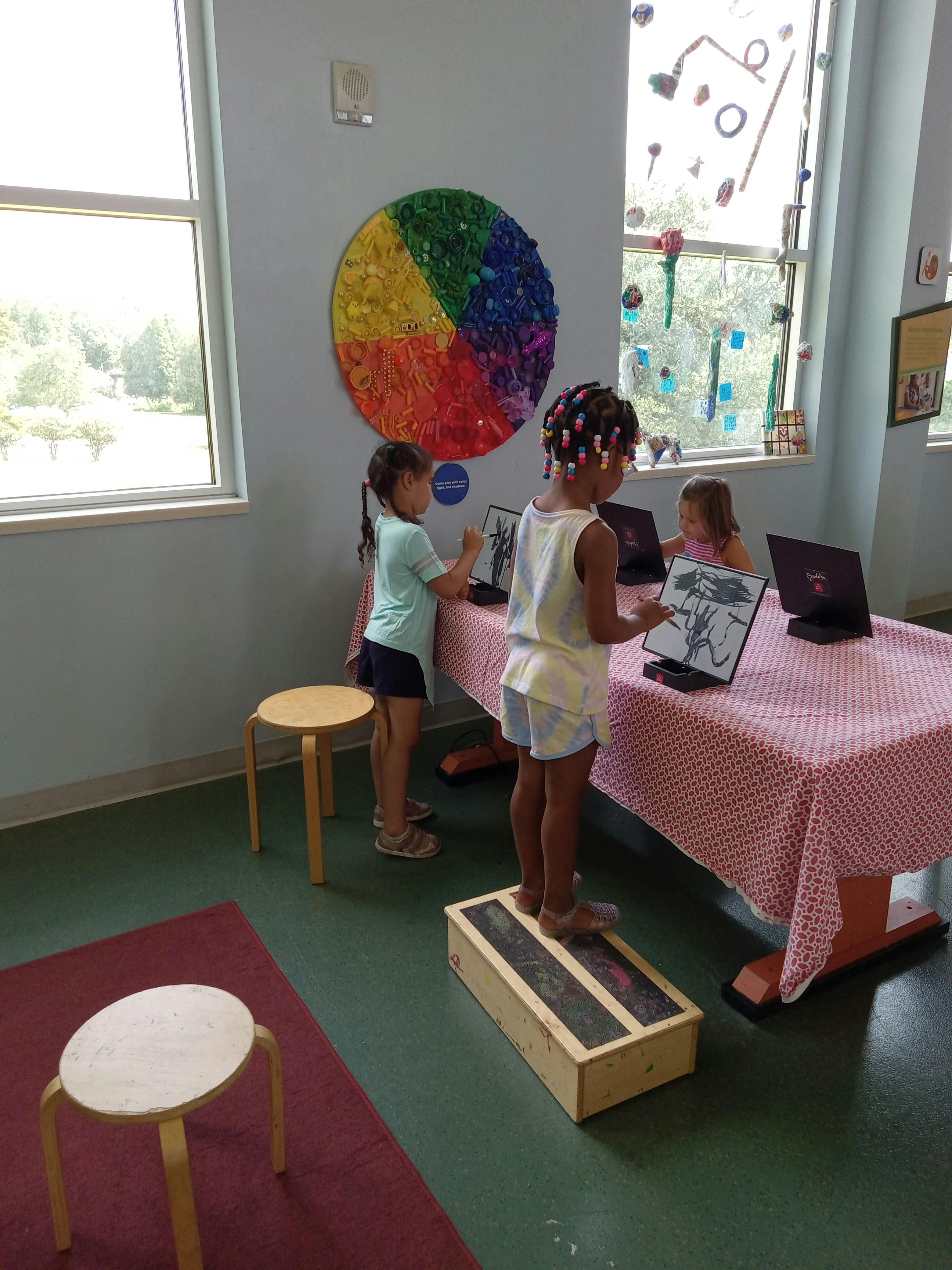 Three children interacting with laptops on a table