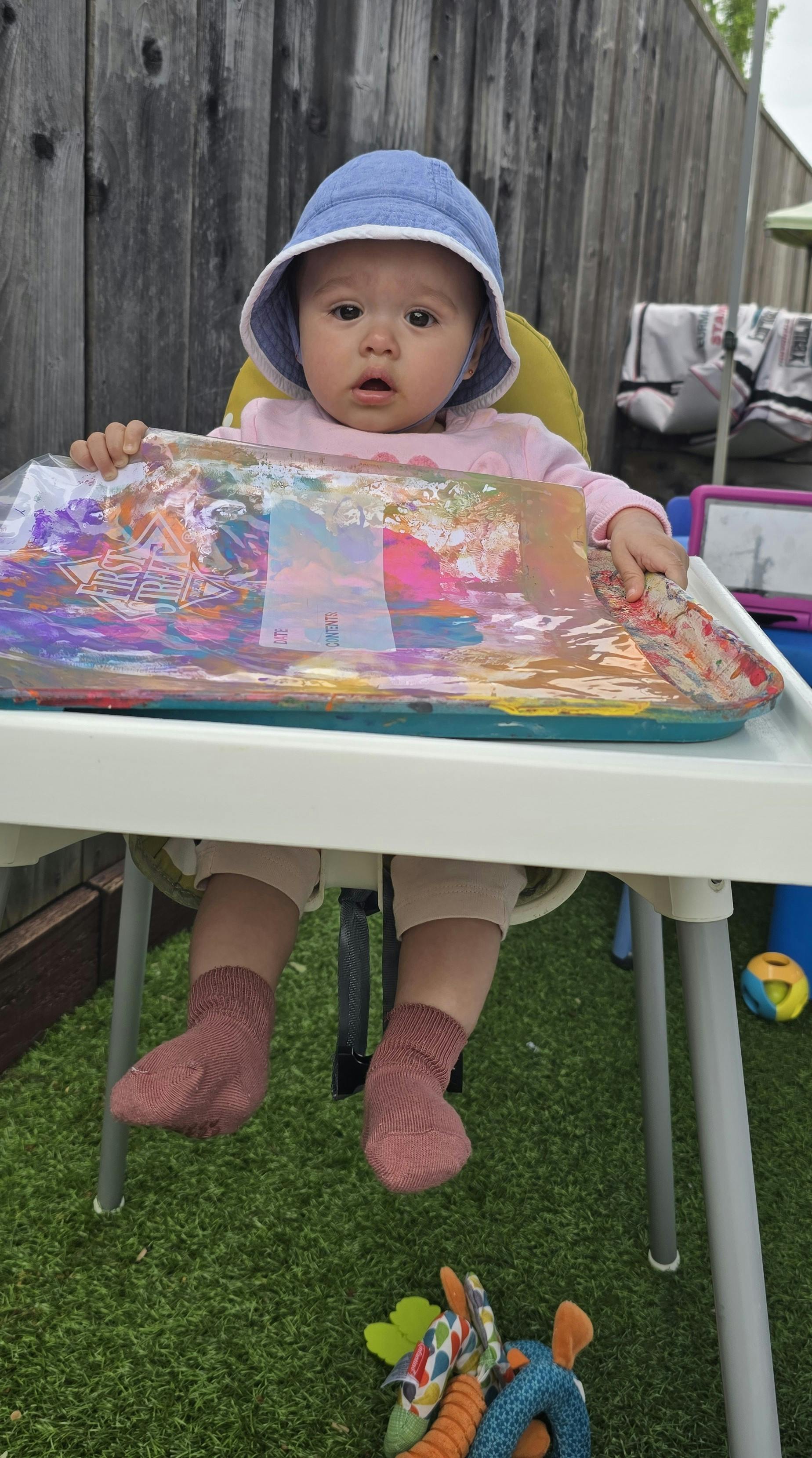 Child in a high chair with a colorful activity mat