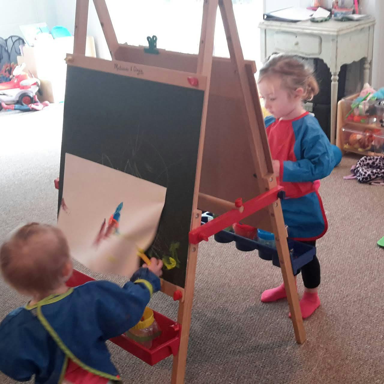 Two children painting at an easel