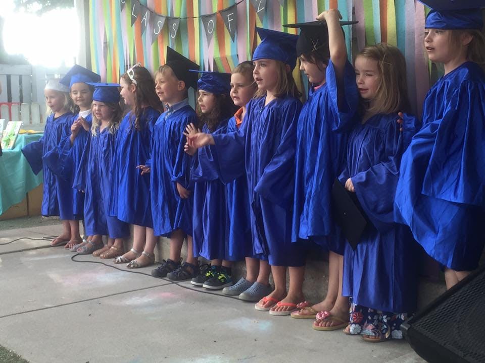 Children in blue graduation gowns and caps standing in a line