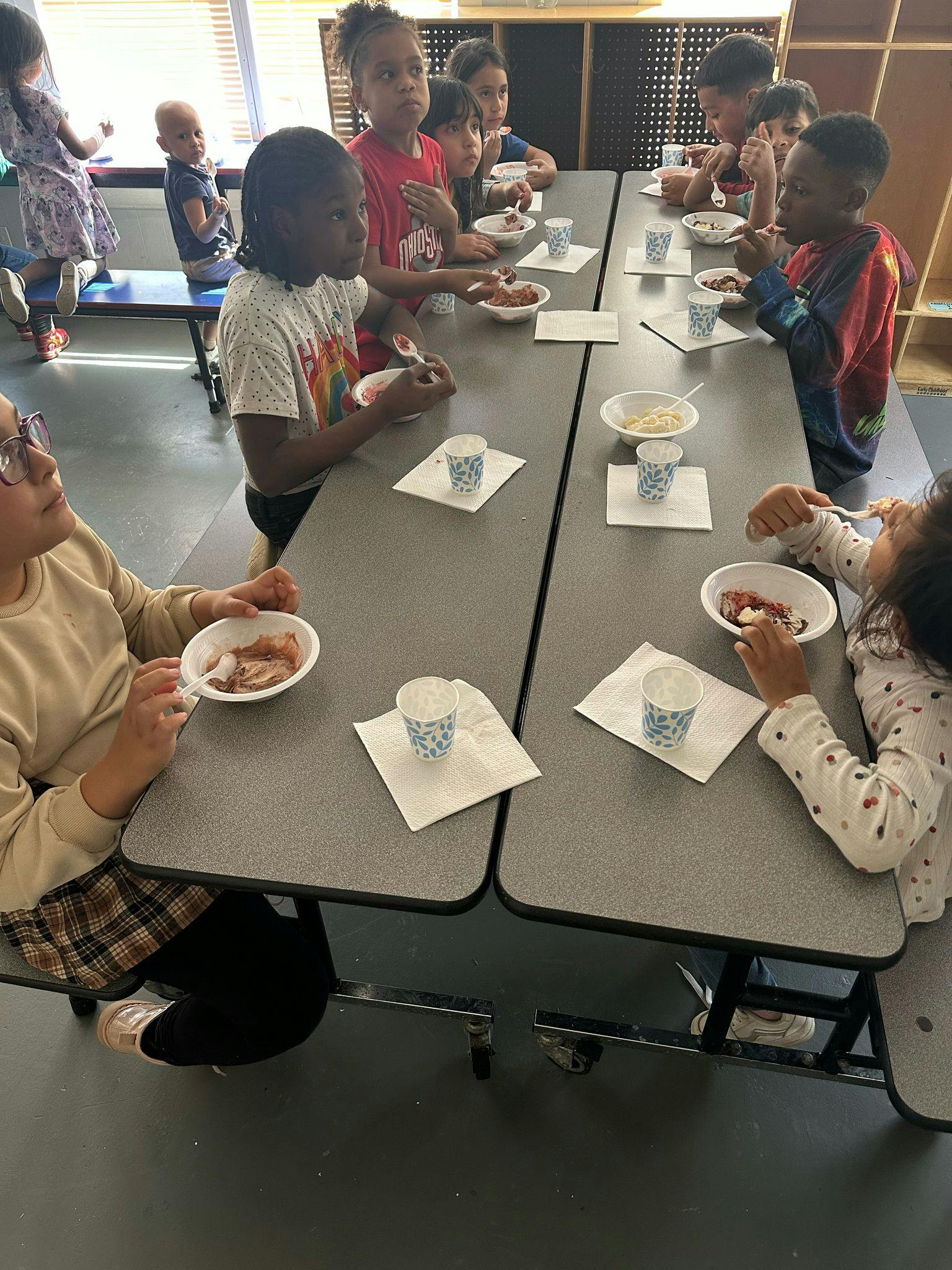 Children sitting at tables eating from a high angle, eating from bowls