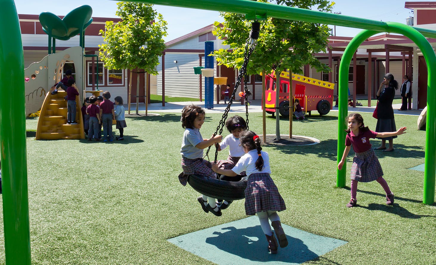 Children playing on a tire swing and playground equipment