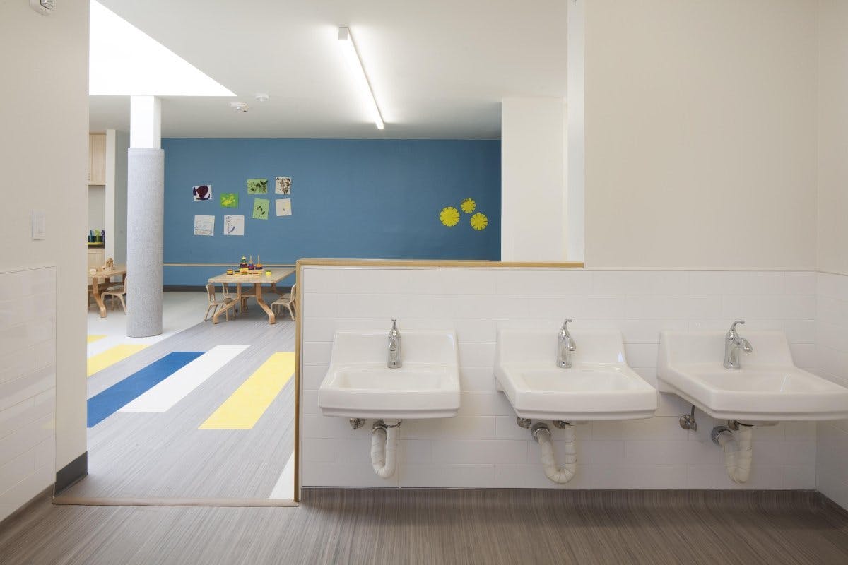 Three sinks in a row with a classroom in the background