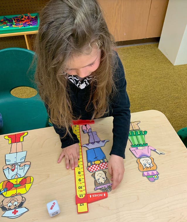 Child playing with stacking puzzle pieces and a ruler on a table