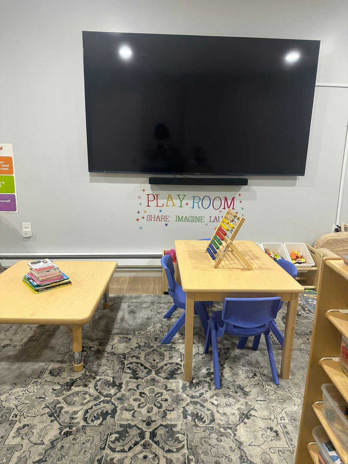 Playroom with a large screen, two tables, and small chairs