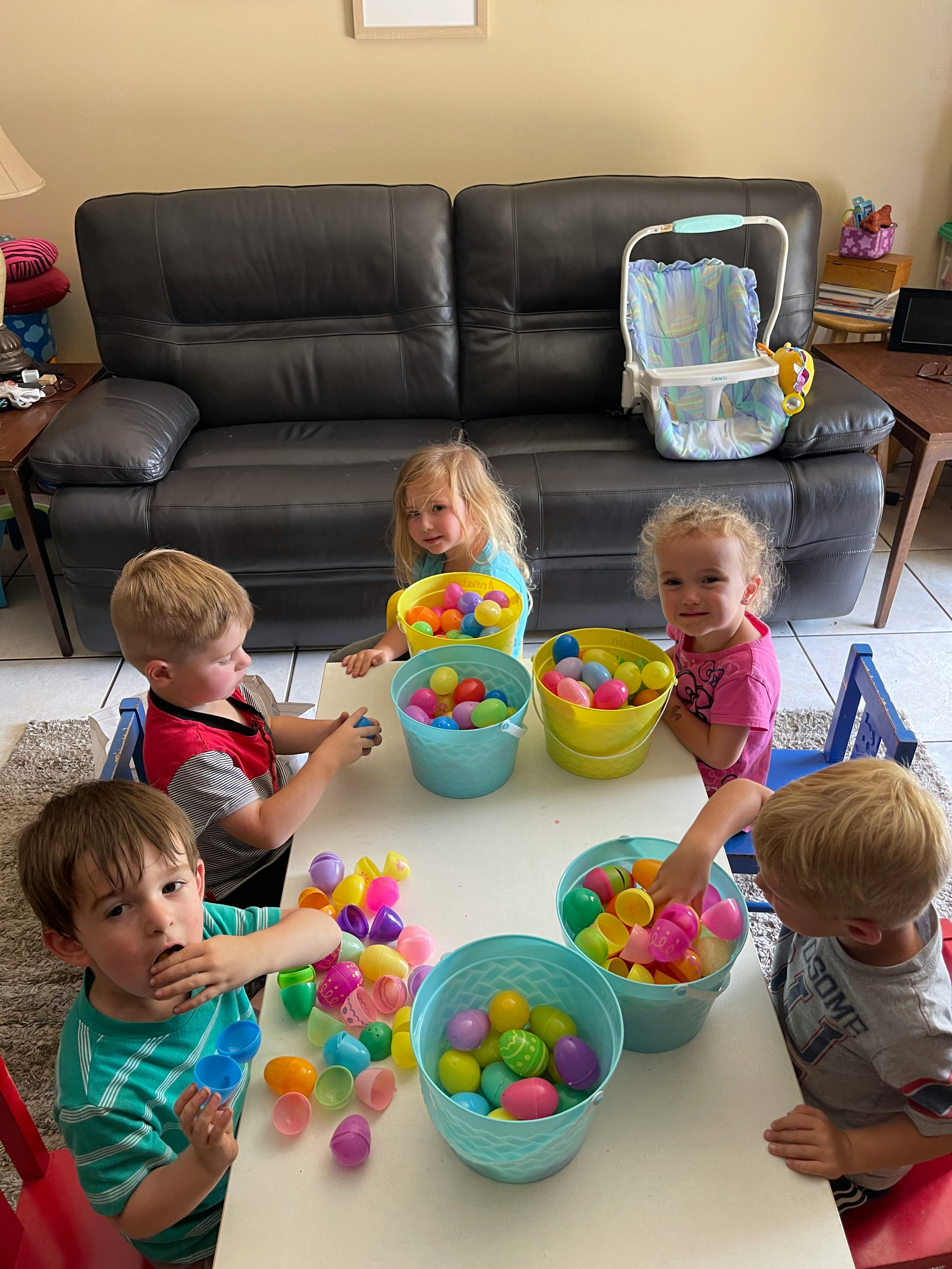 Children at a table with buckets of colorful plastic eggs