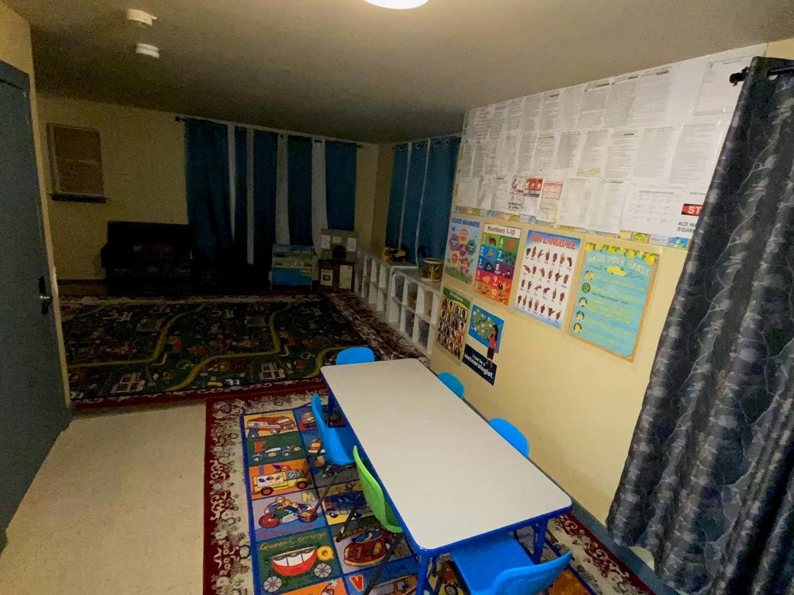 Classroom with a long table and chairs, colorful rugs, and posters on the wall