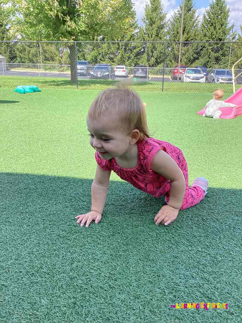 Child crawling on green turf