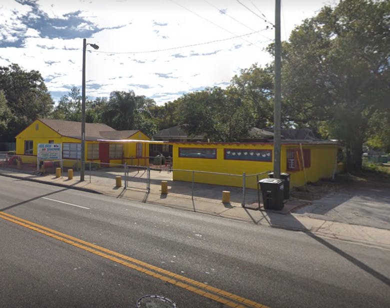 Yellow building with a red awning next to a road