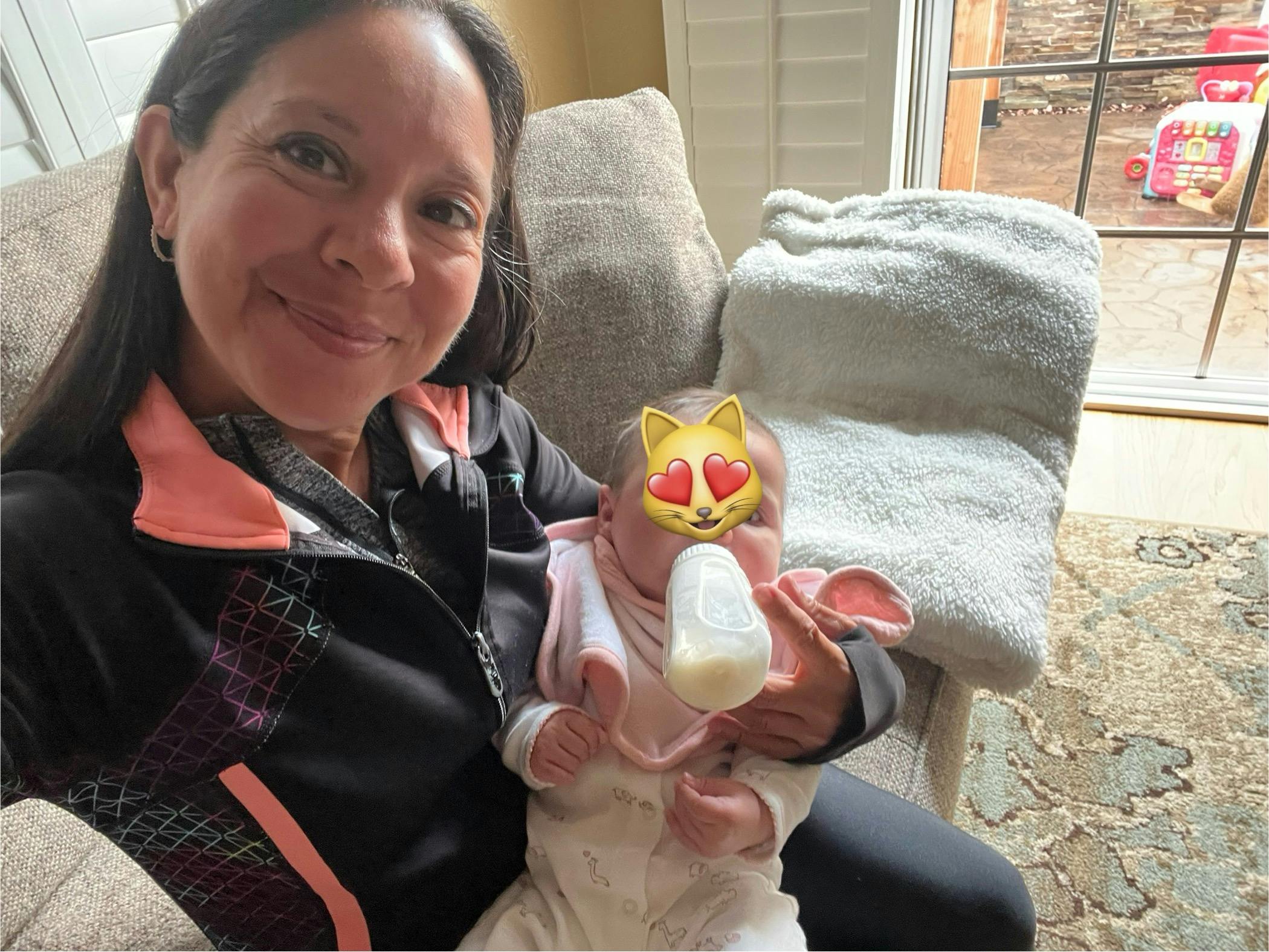 Person holding and bottle feeding a baby on a couch
