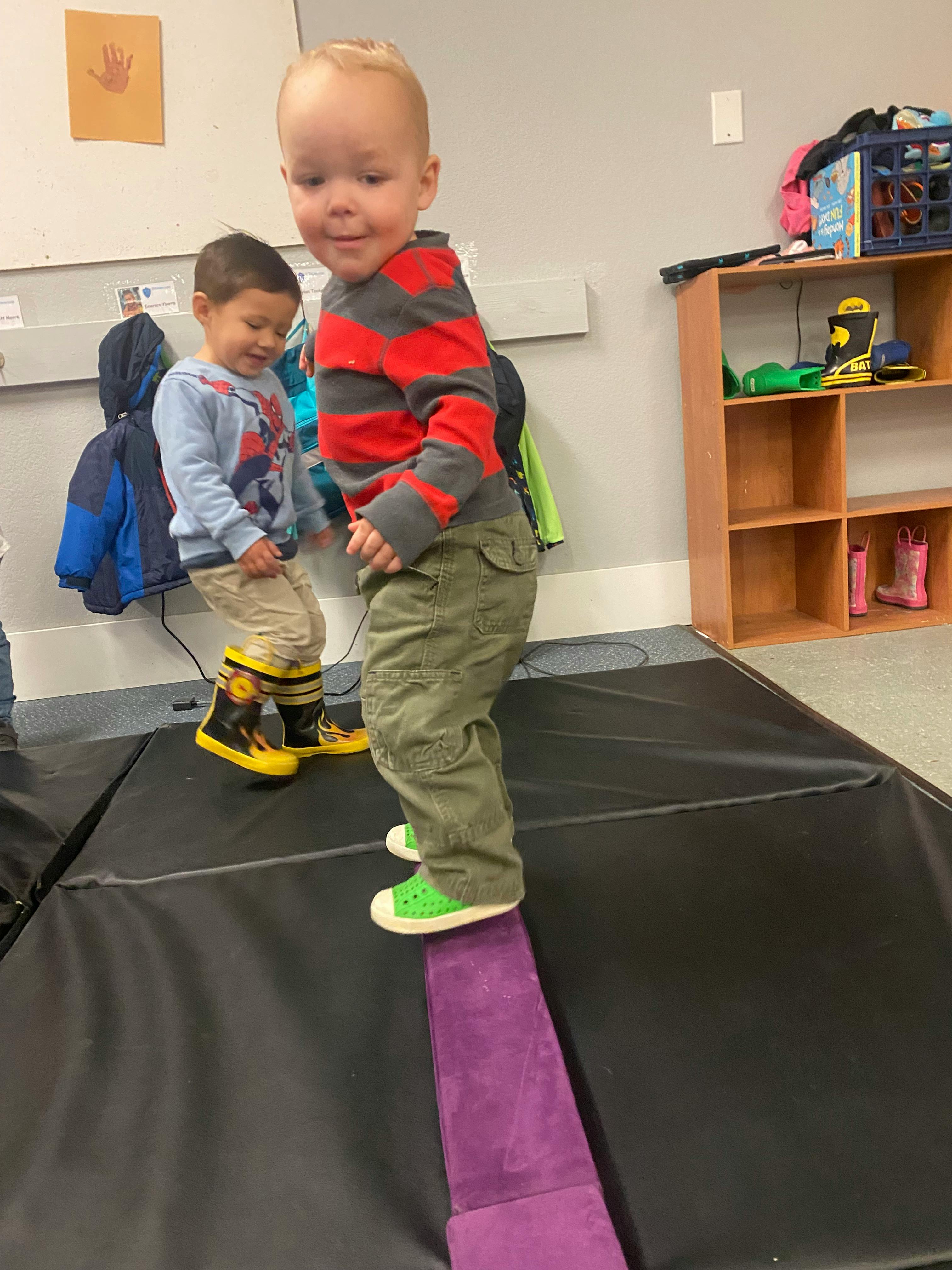 Two children playing on soft play equipment in a room