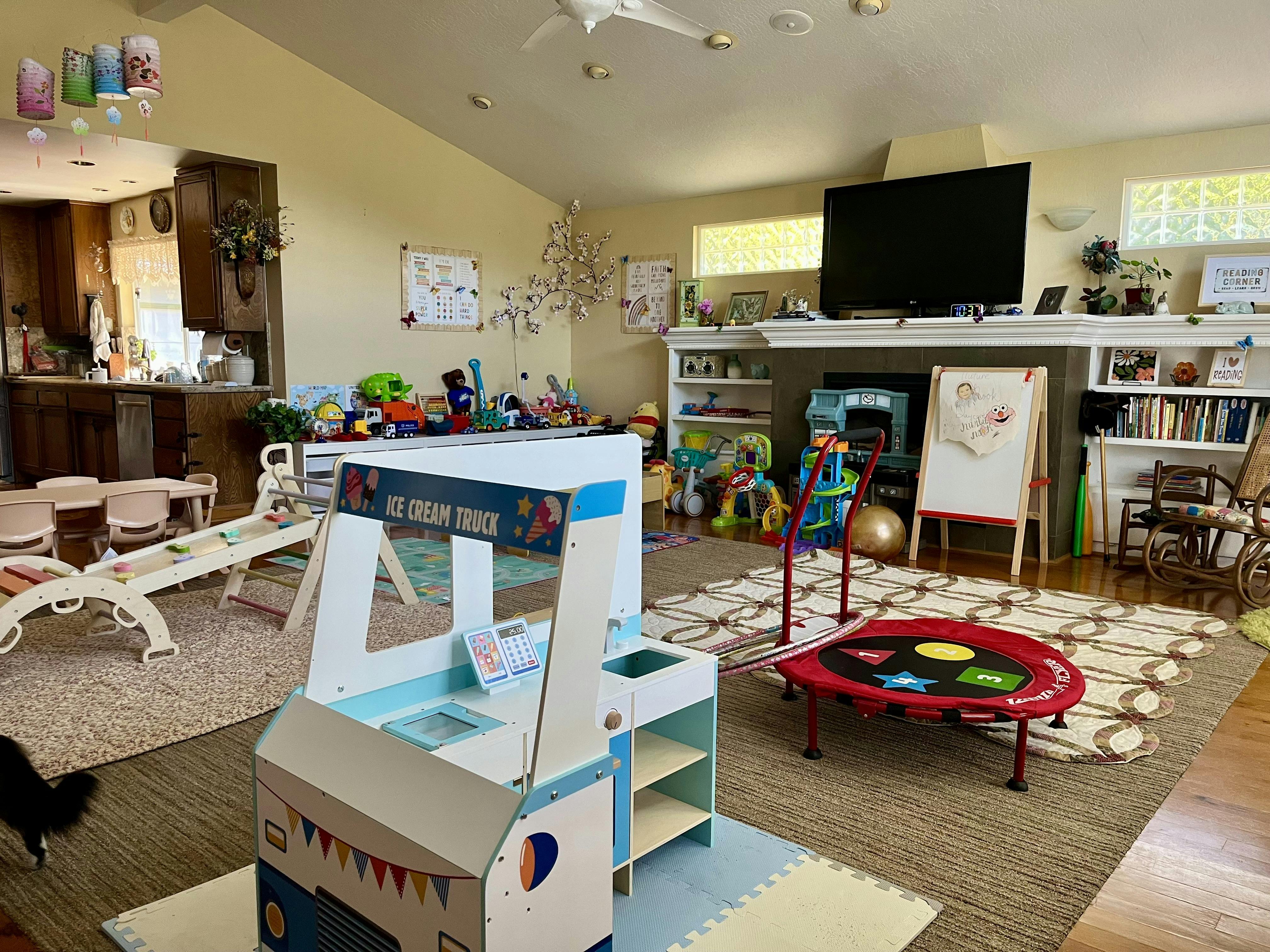 A playroom with an ice cream truck toy, trampoline, and other children's toys