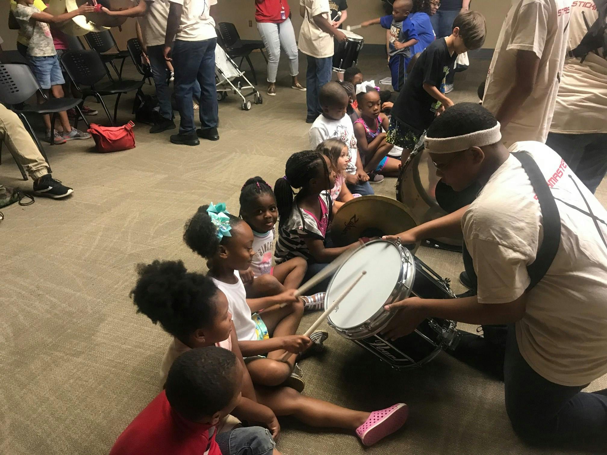 Person teaching children to play drums