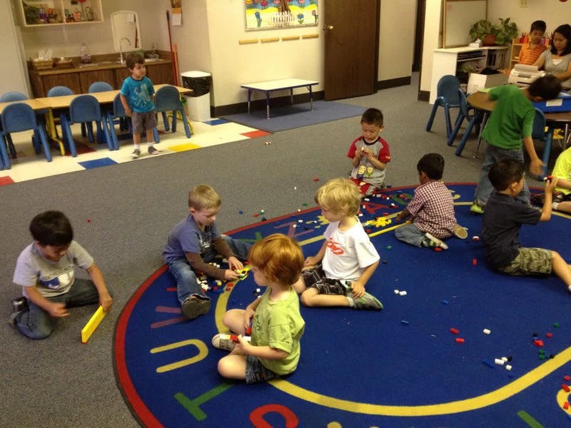 Children playing with blocks on a rug in a classroom