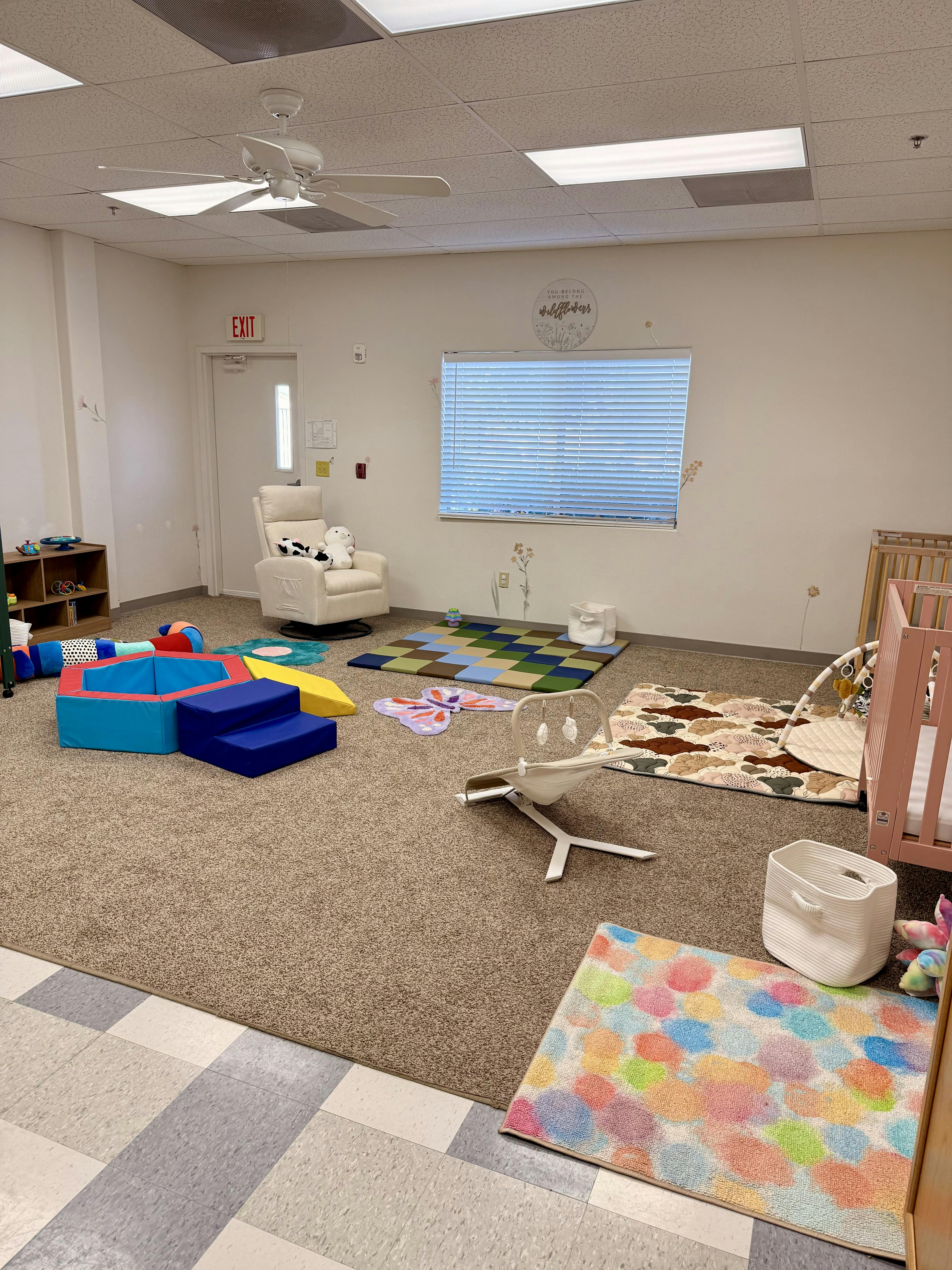 Playroom with soft play equipment, rugs, and a crib