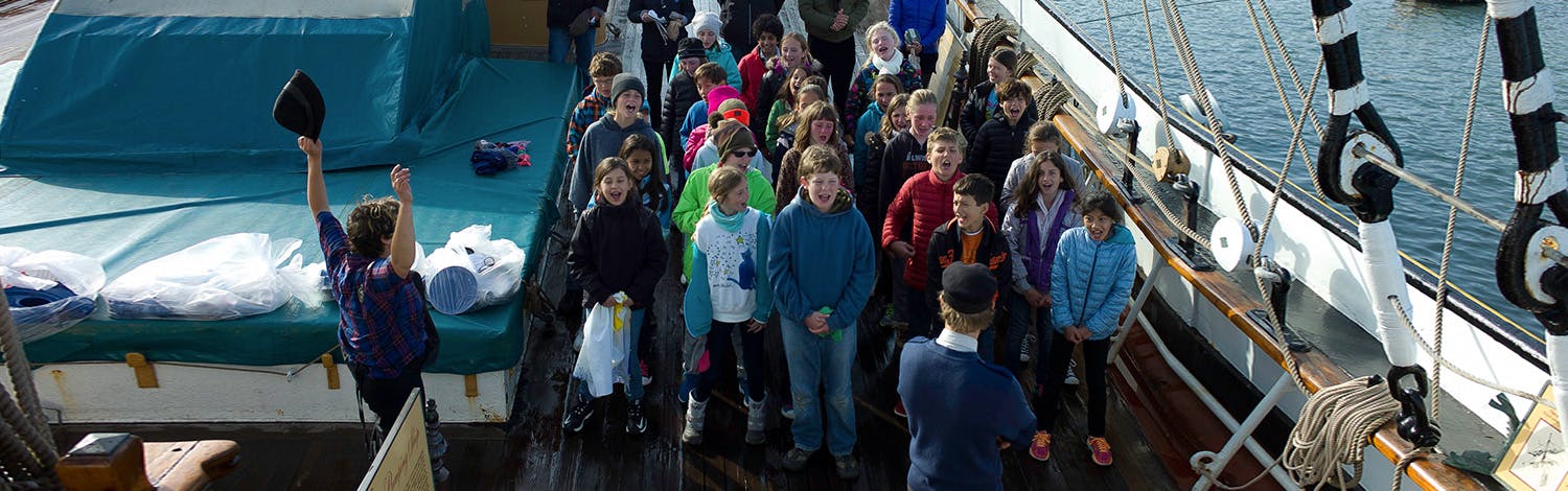 Children on a ship deck with one child raising a hat in the air