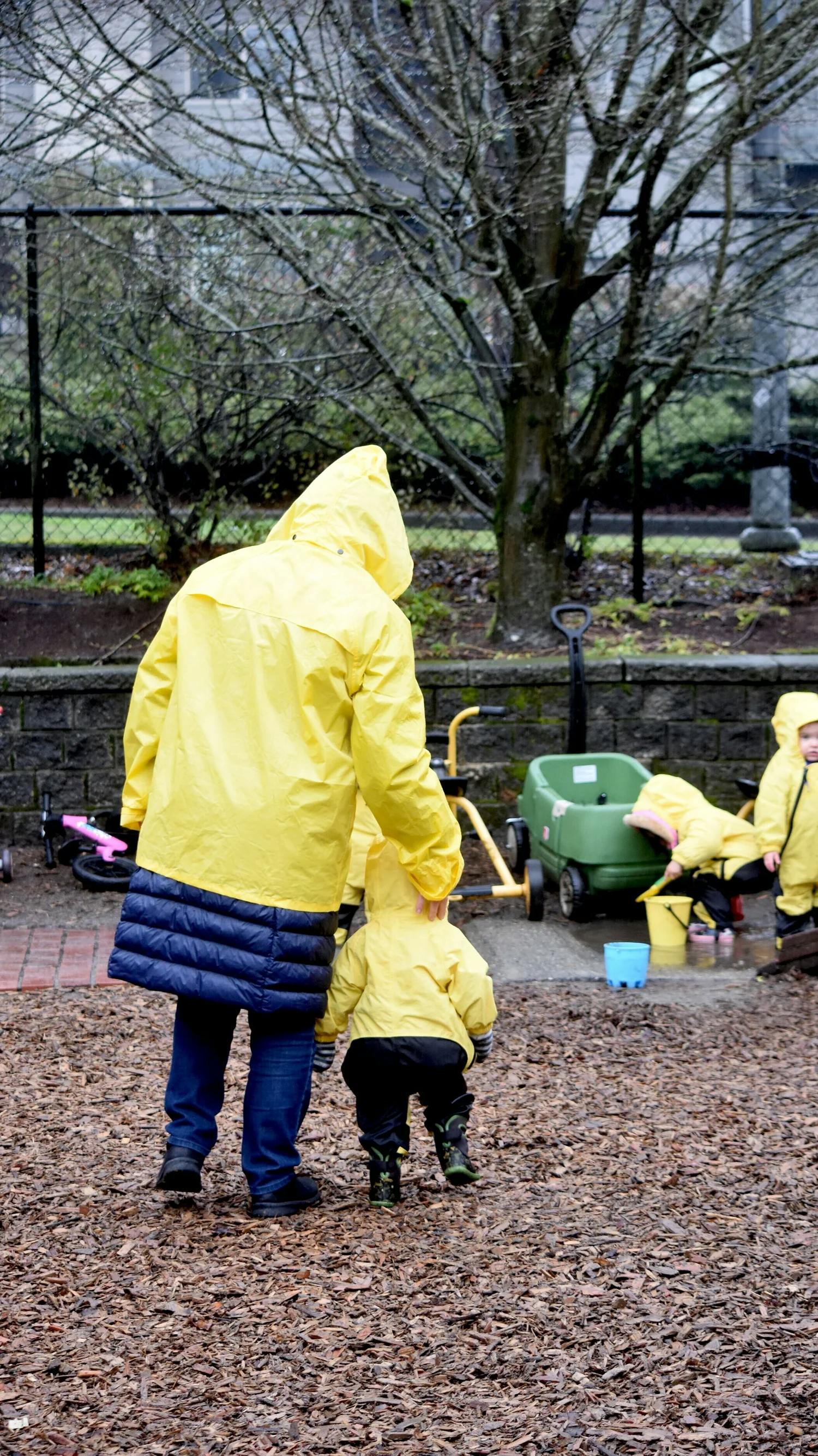 Adult and children in yellow raincoats on a playground