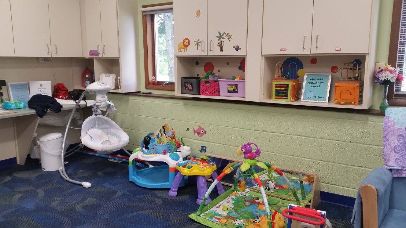 Room with baby swing, play mat, and toys