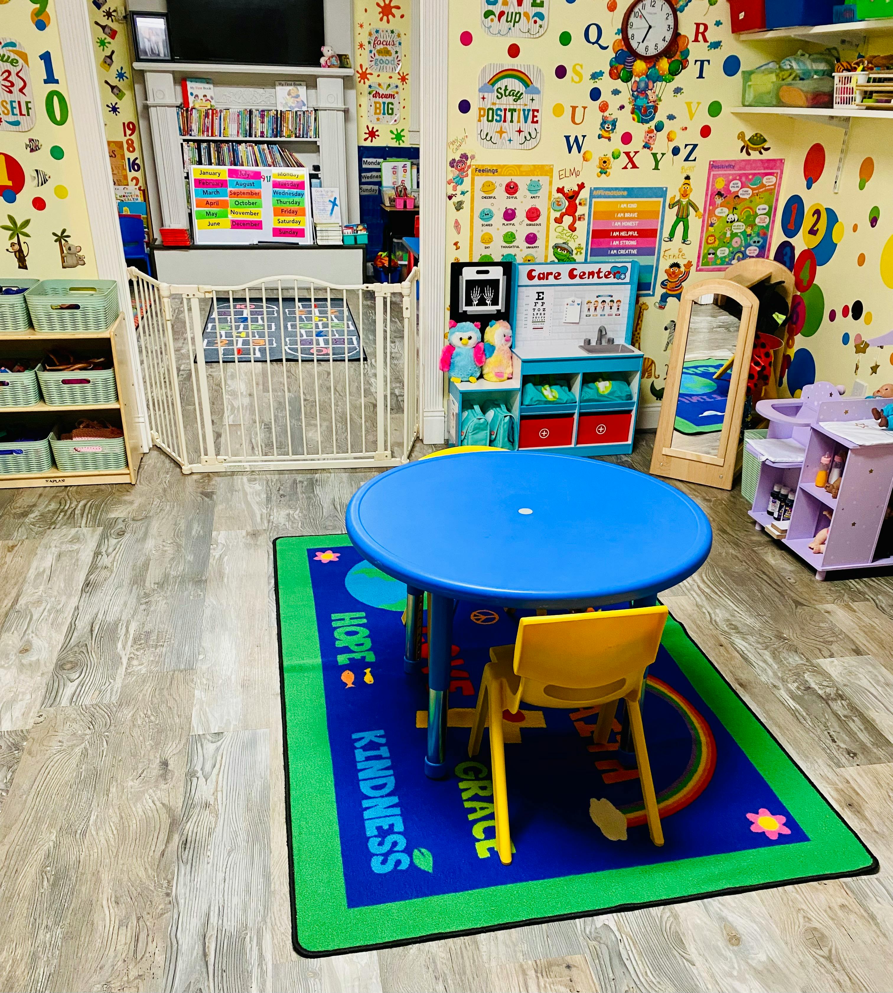 Classroom play area with blue table and yellow chair on a colorful rug
