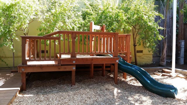 Wooden playground structure with a green slide