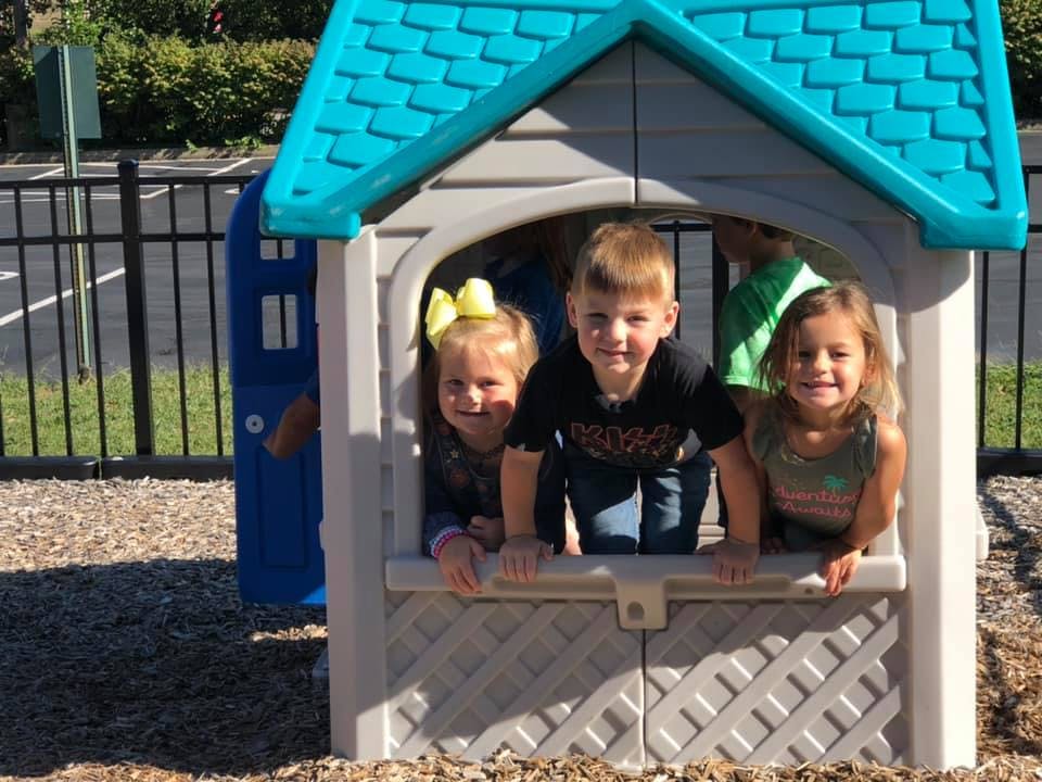 Three children looking out of a playhouse window
