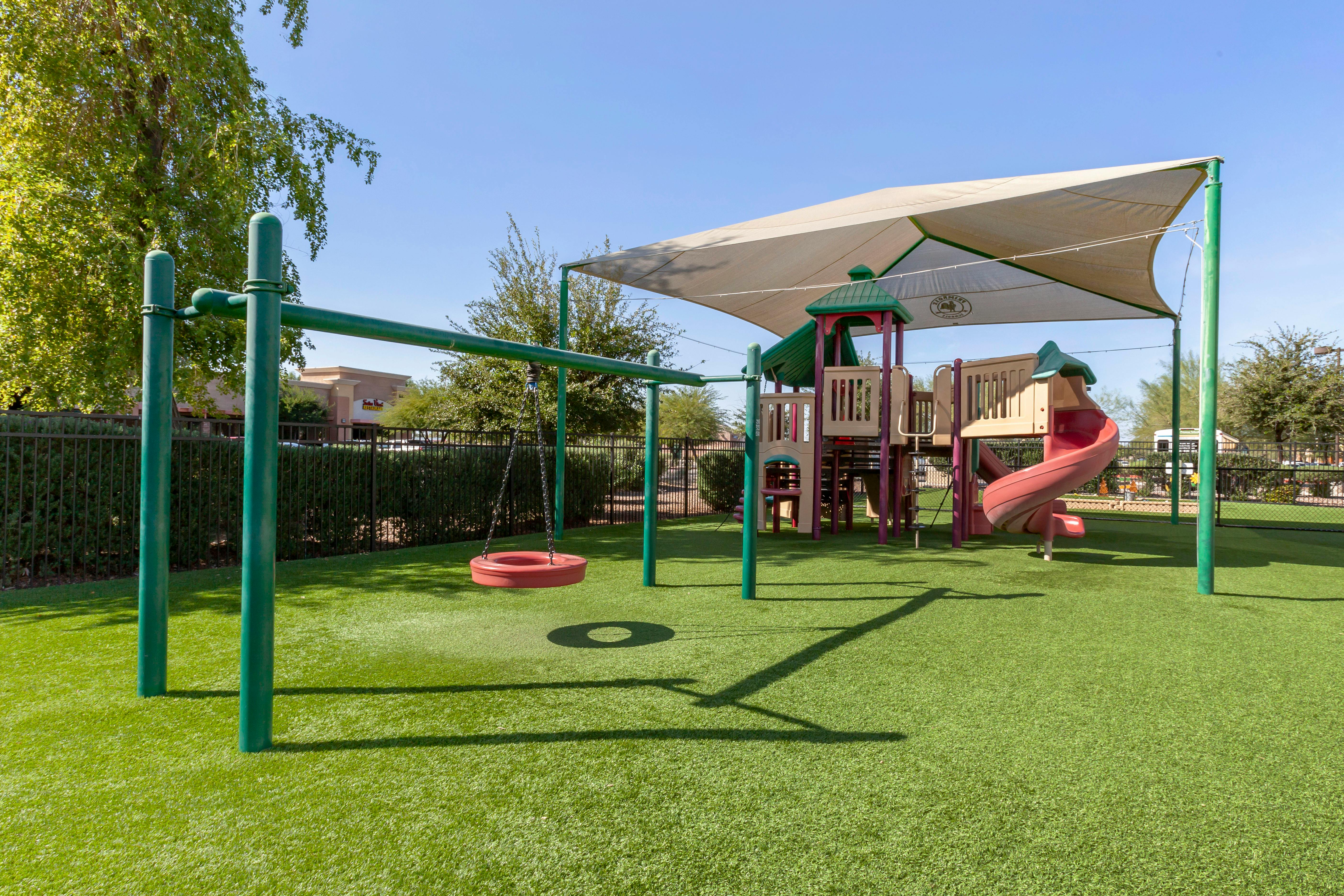 Playground with swings, slides, climbing structures, and a sun shade