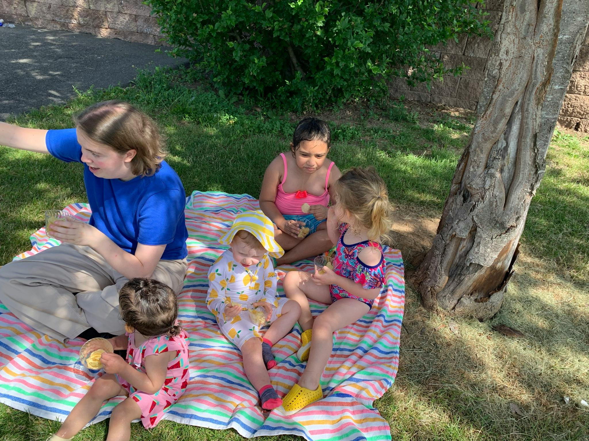 Person and children sitting on a blanket outdoors