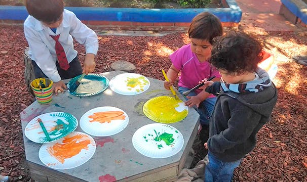 Three children painting on paper plates