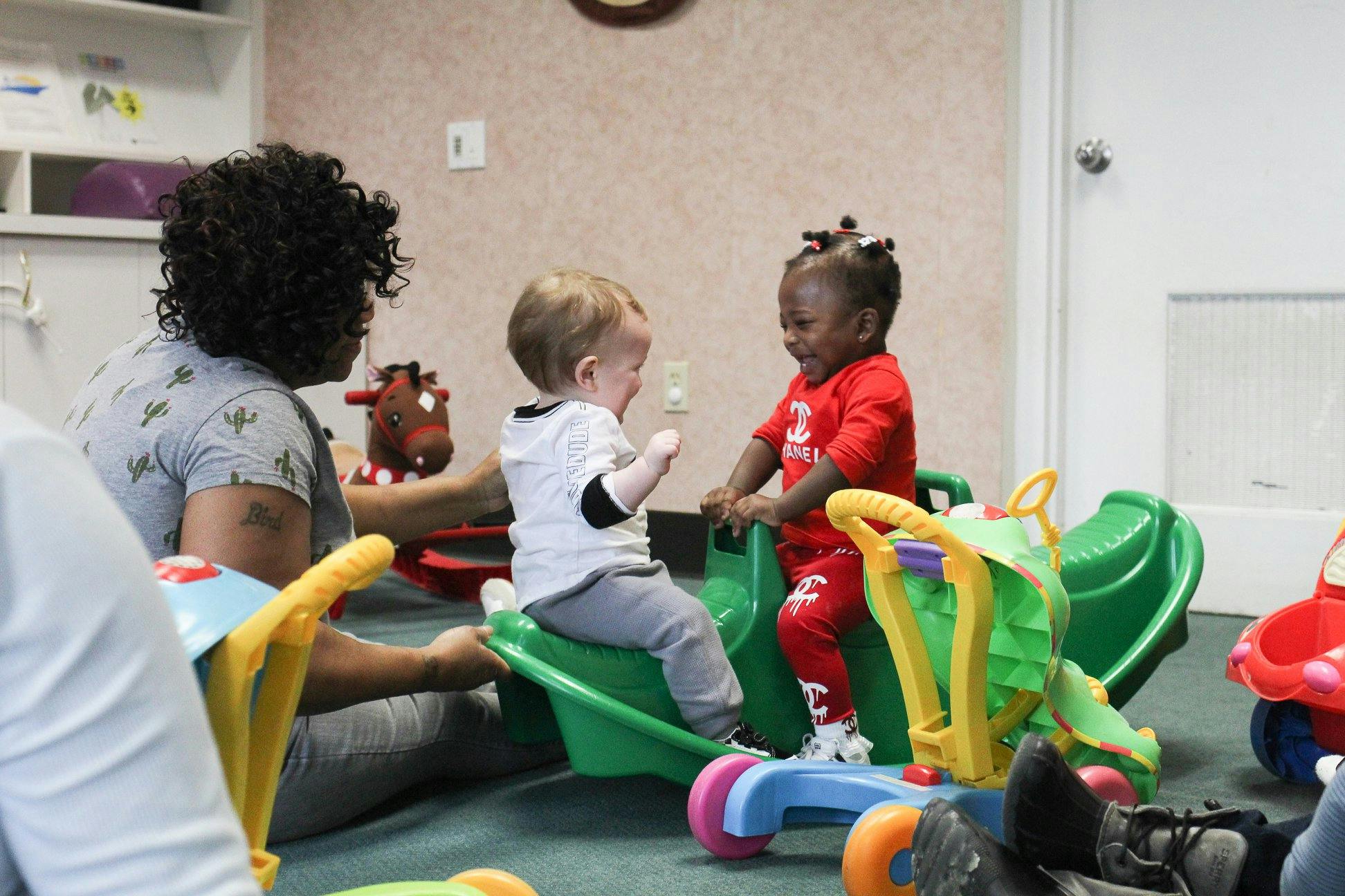 Adult and two children playing with toys in a room