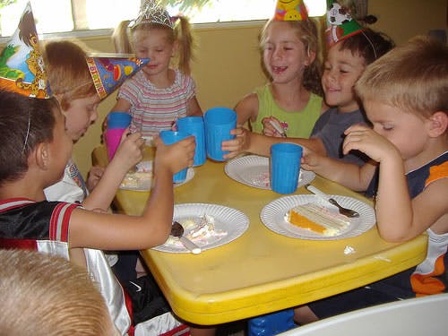 Children at a table with cake and drinks