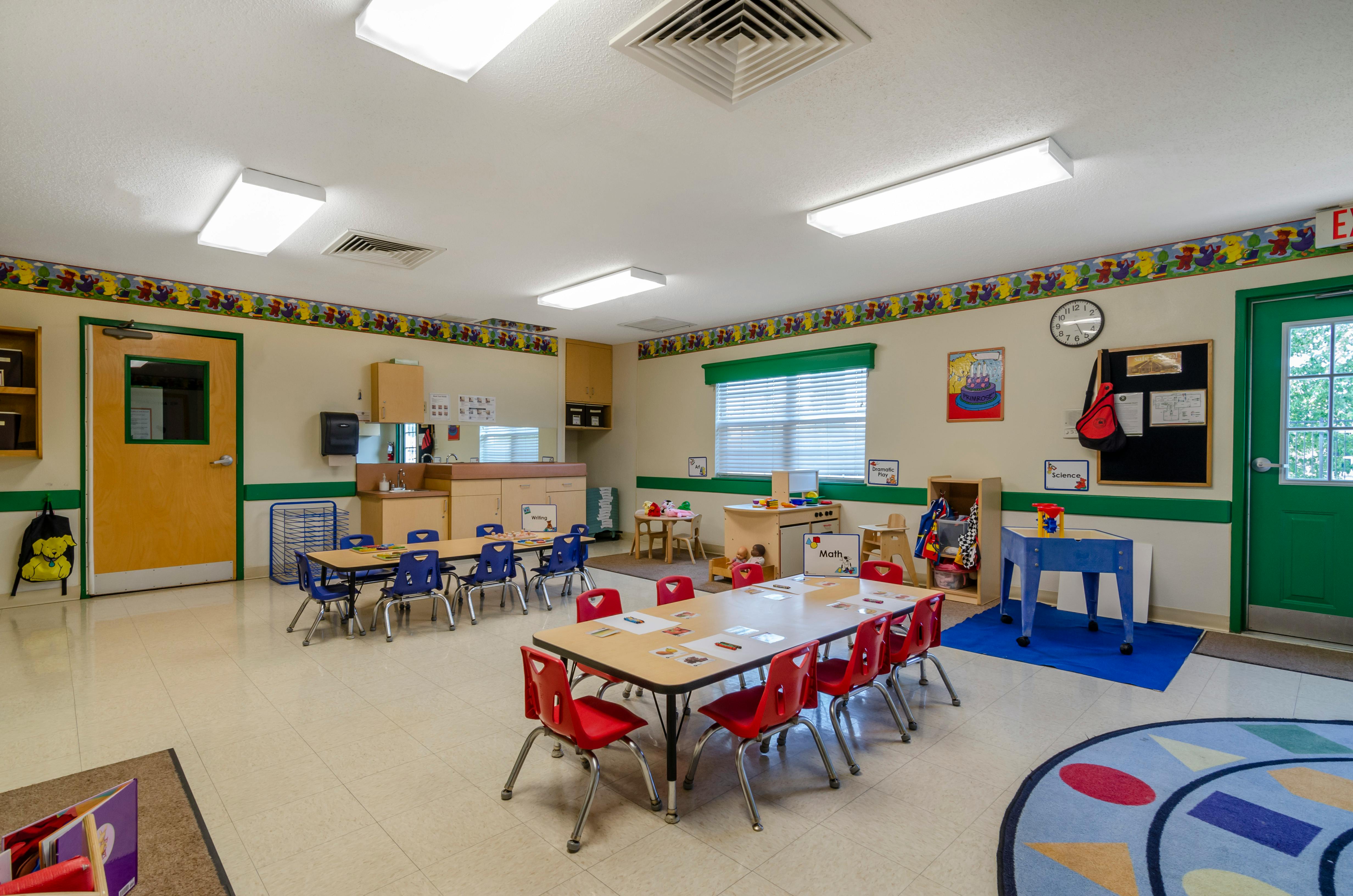 An empty early childhood classroom with multiple tables and chairs