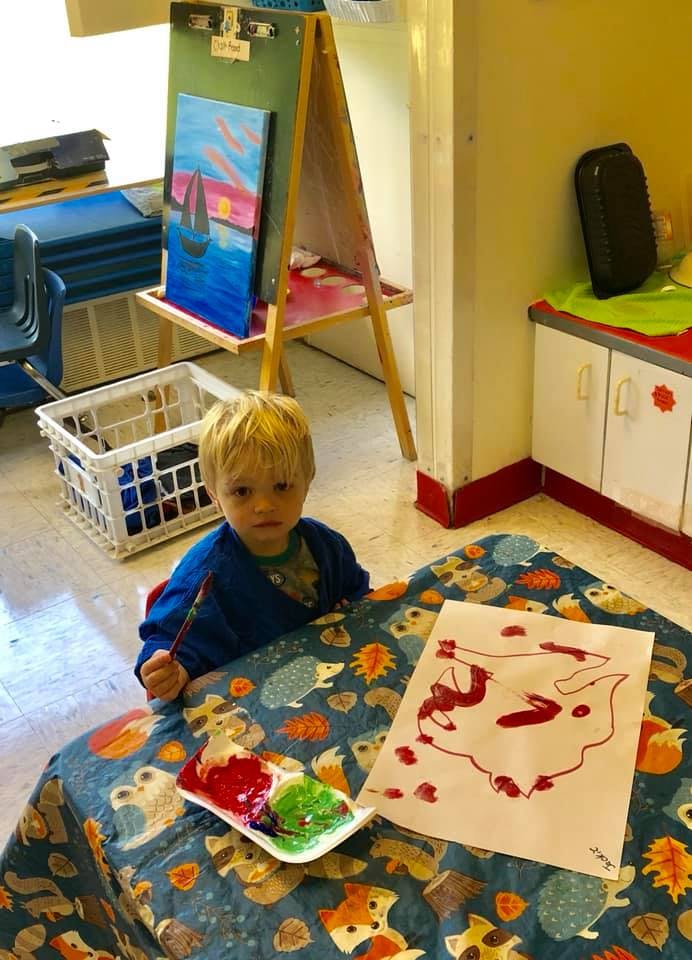 Child painting at a table in a classroom