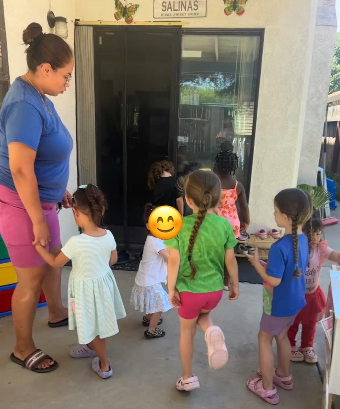 A person standing with several children on a patio near a sliding glass door