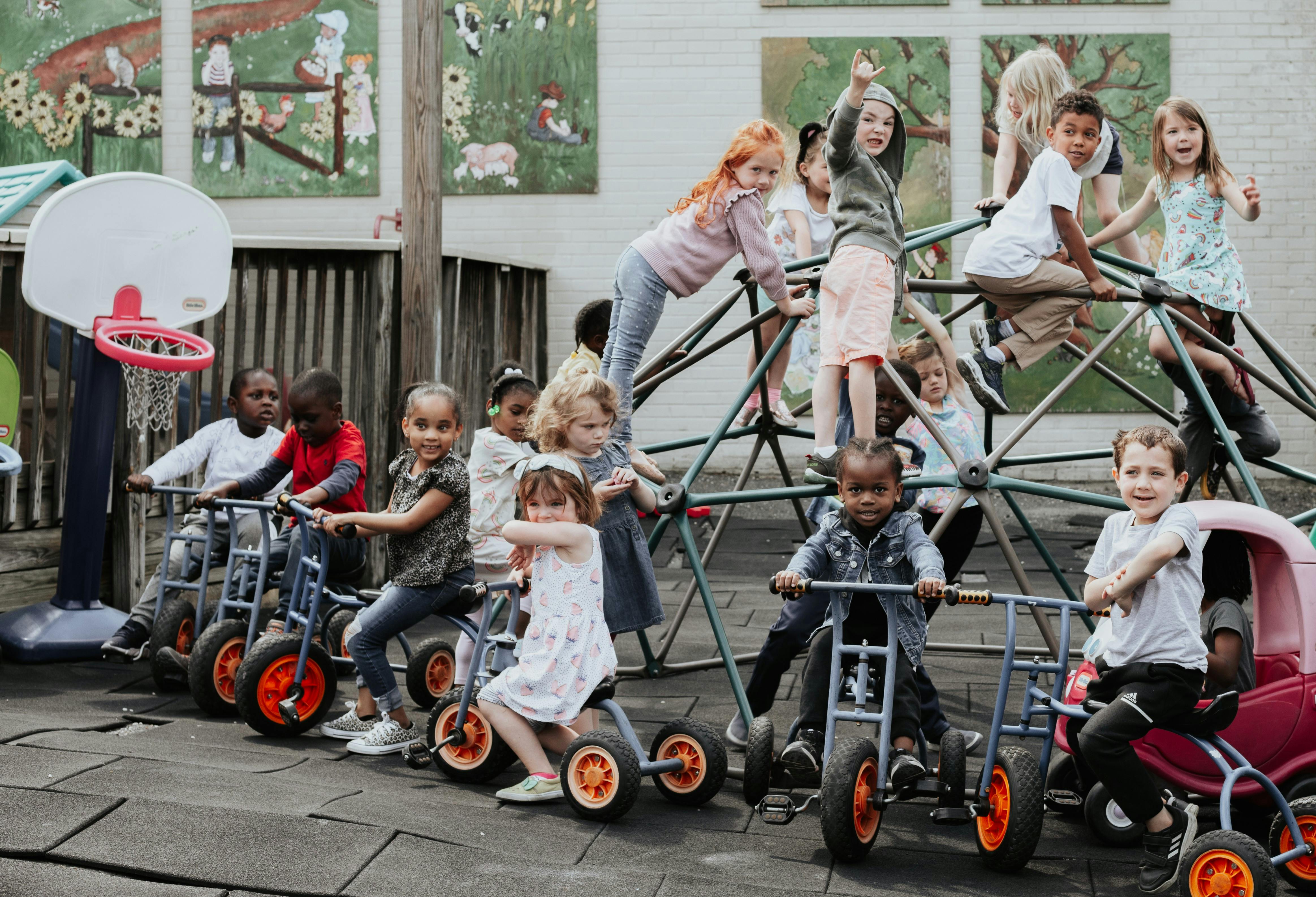 Children playing on tricycles and a climbing dome
