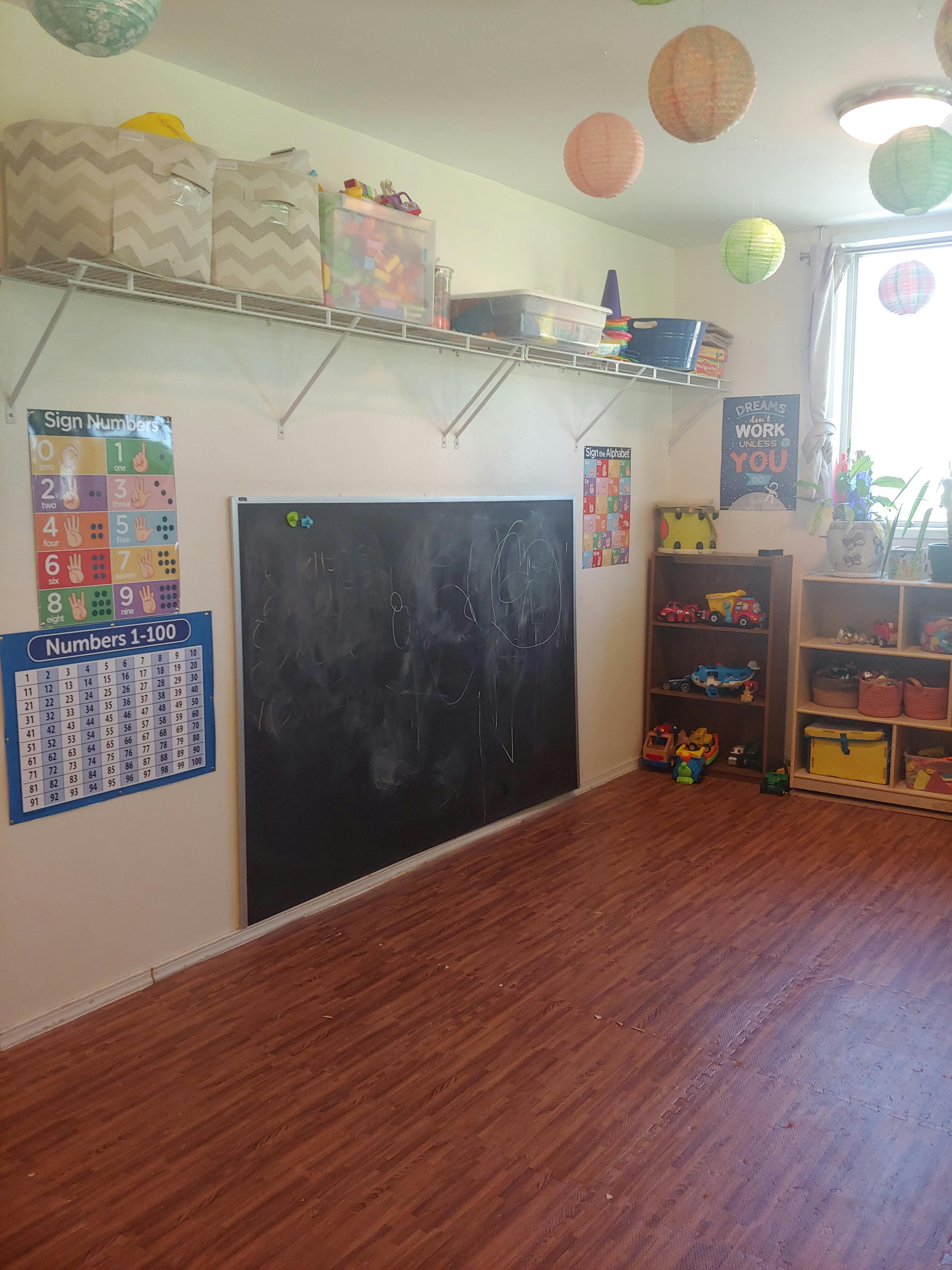 Classroom with a chalkboard, educational posters, and shelves with toys
