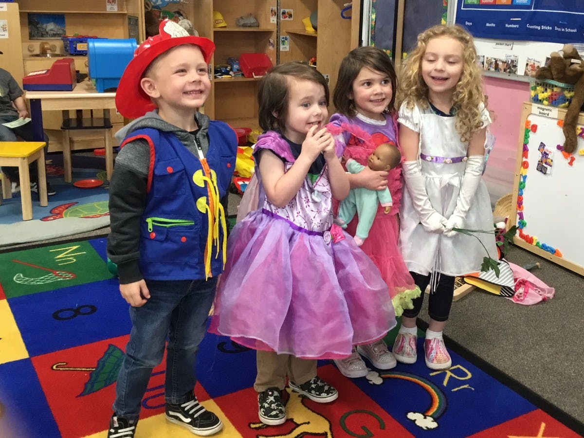 Four children in costumes standing in a classroom