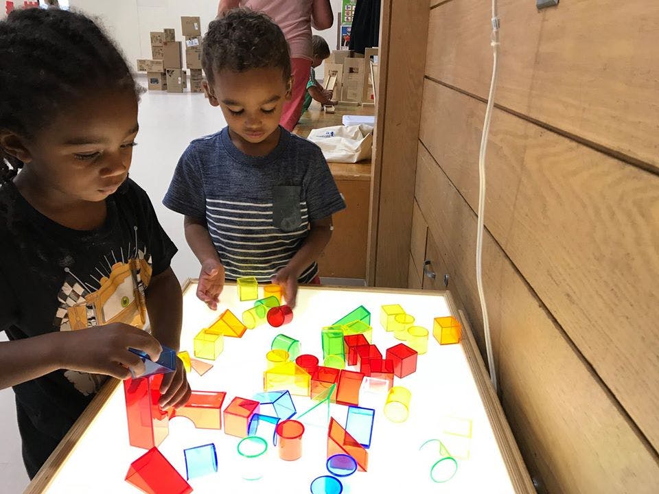 Two children playing with colorful translucent blocks on a light table