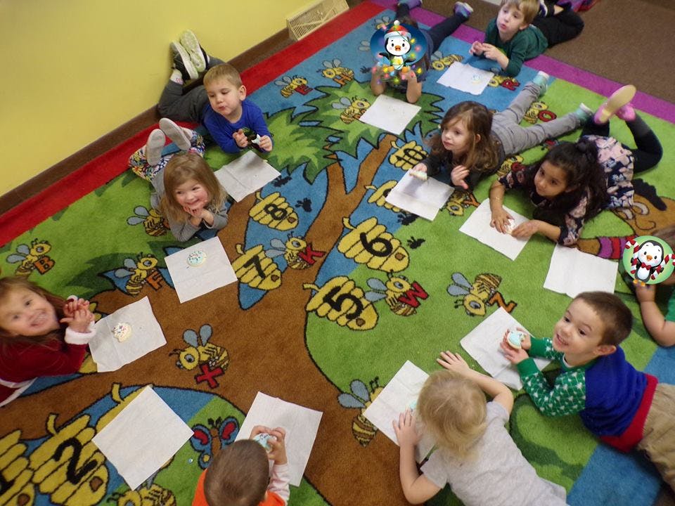 Children lying on a colorful rug with papers