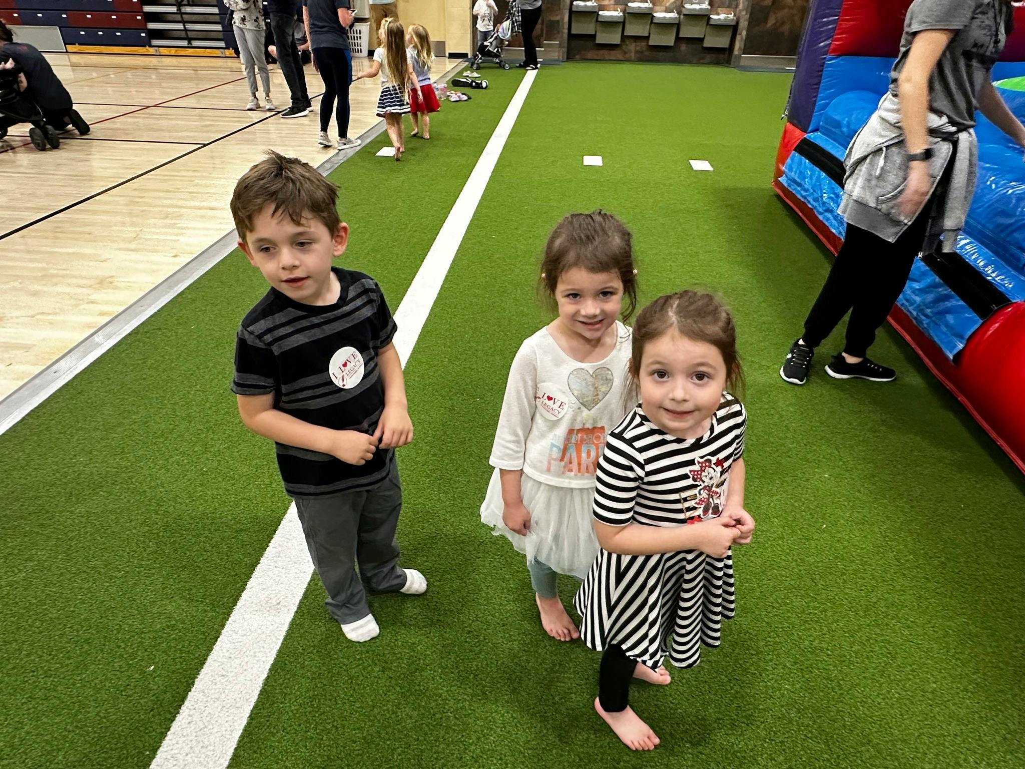 Three children standing on green turf
