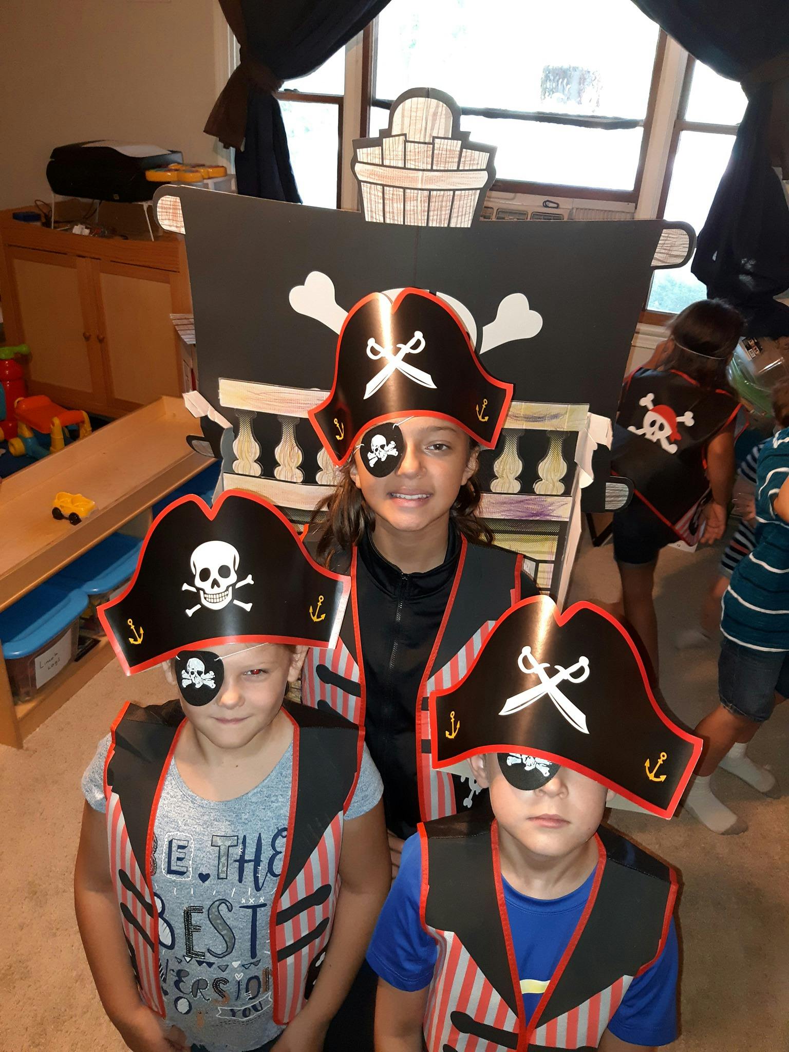 Three children in pirate costumes with eye patches and hats