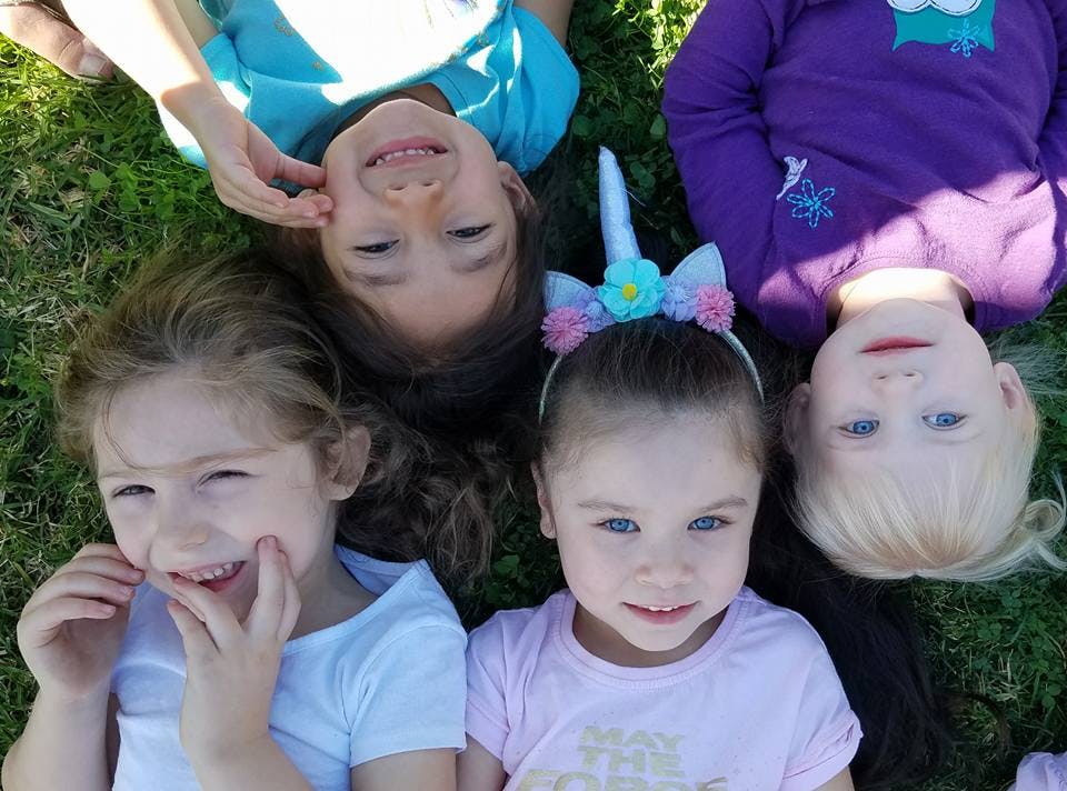 Four children lying on grass looking up