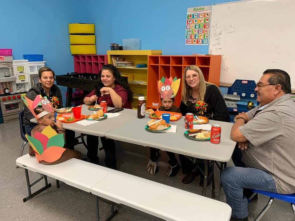 People and children eating at a table in a classroom
