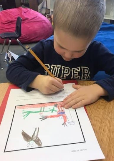 Child writing on paper with a pencil