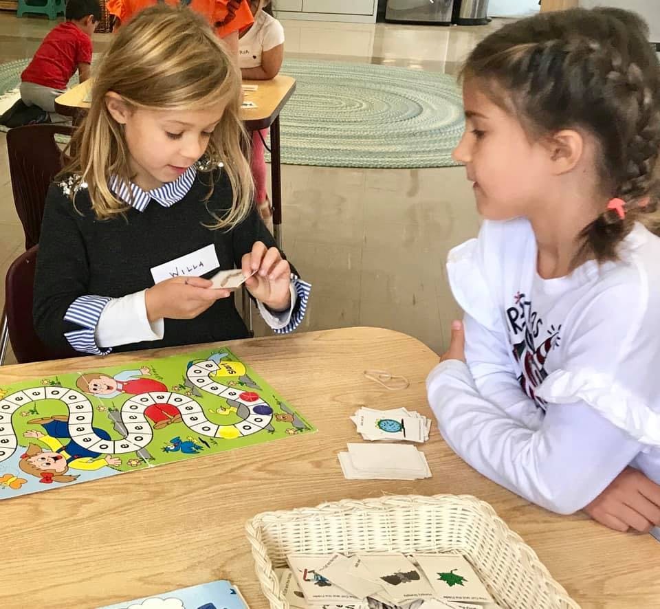 Two children playing a board game at a table